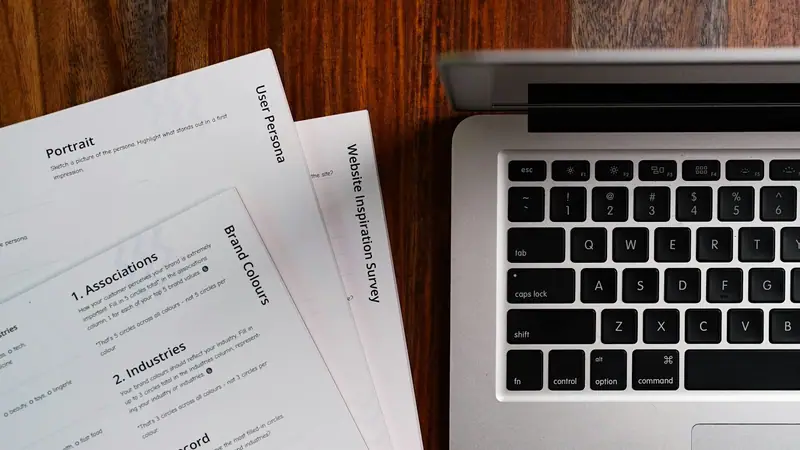 Documents posés à côté d’un ordinateur portable